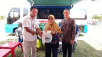 Staff PT Timah Tbk berpose dengan salah satu warga